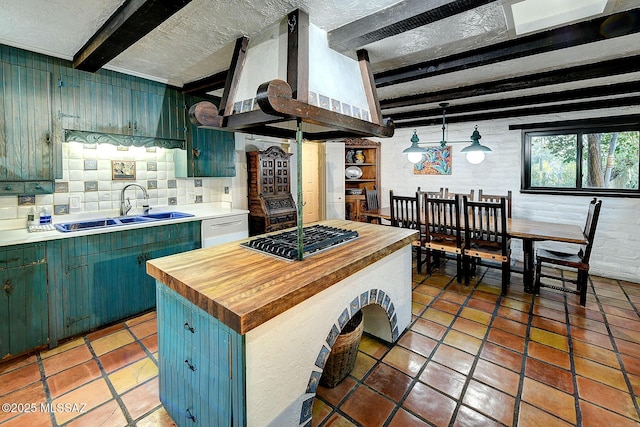 kitchen featuring beamed ceiling, stainless steel gas stovetop, sink, dishwashing machine, and exhaust hood