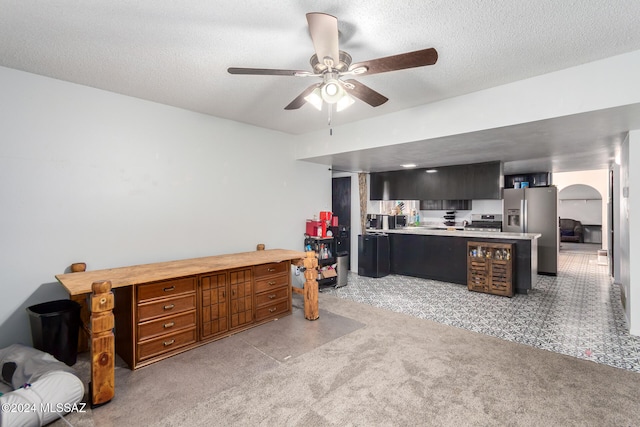 carpeted office featuring a textured ceiling and ceiling fan