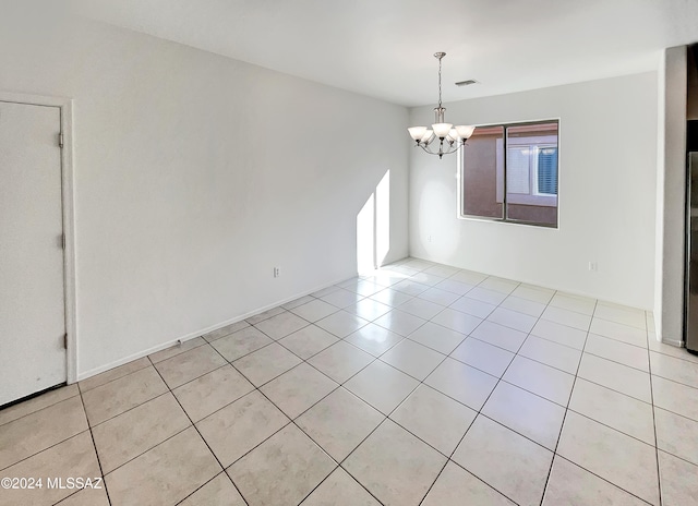 tiled spare room with a chandelier