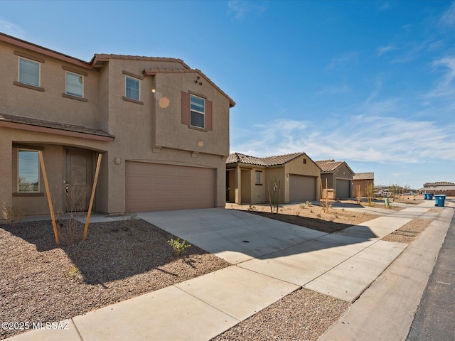 view of front facade with stucco siding, a garage, concrete driveway, and a tile roof