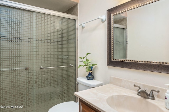 bathroom with vanity, toilet, and a shower with door