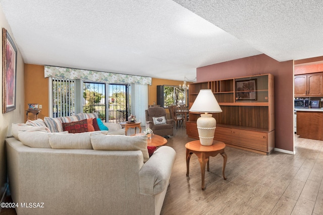 living room with light hardwood / wood-style floors, a textured ceiling, and a chandelier