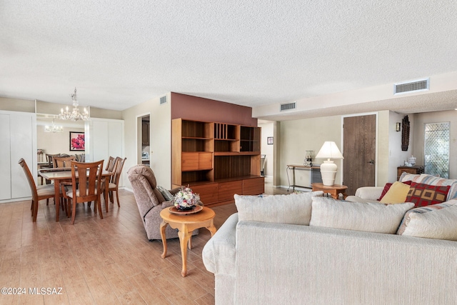 living room with light hardwood / wood-style flooring, a textured ceiling, and a notable chandelier