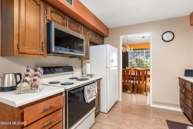 kitchen with white appliances, a notable chandelier, and light wood-type flooring