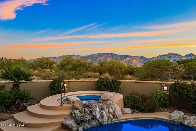 pool at dusk featuring a mountain view