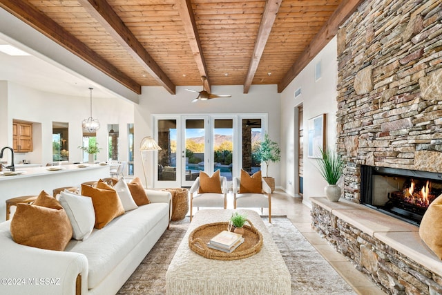 tiled living room featuring beamed ceiling, wood ceiling, a fireplace, and french doors