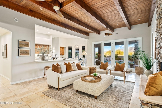 living room featuring beamed ceiling, light tile patterned floors, ceiling fan, and wood ceiling