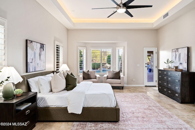 bedroom with ceiling fan, access to outside, and a tray ceiling