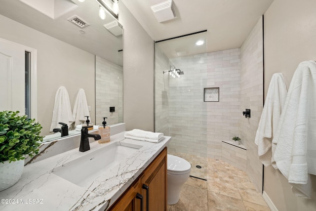 bathroom featuring a tile shower, vanity, and toilet