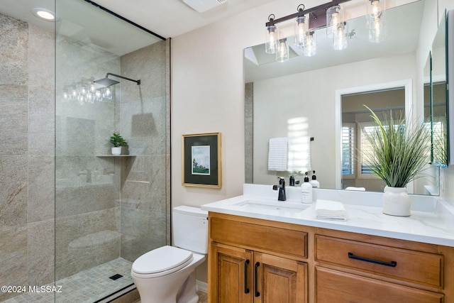 bathroom with a tile shower, vanity, and toilet