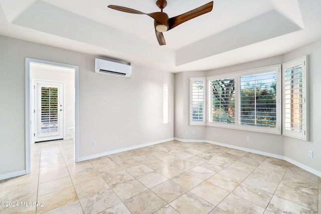 empty room with a tray ceiling, an AC wall unit, and ceiling fan