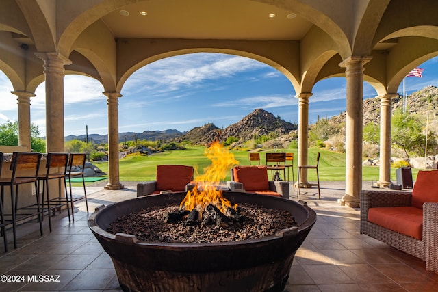 view of patio with a mountain view, a bar, and an outdoor fire pit