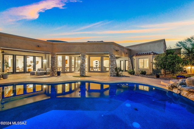 pool at dusk with a patio area