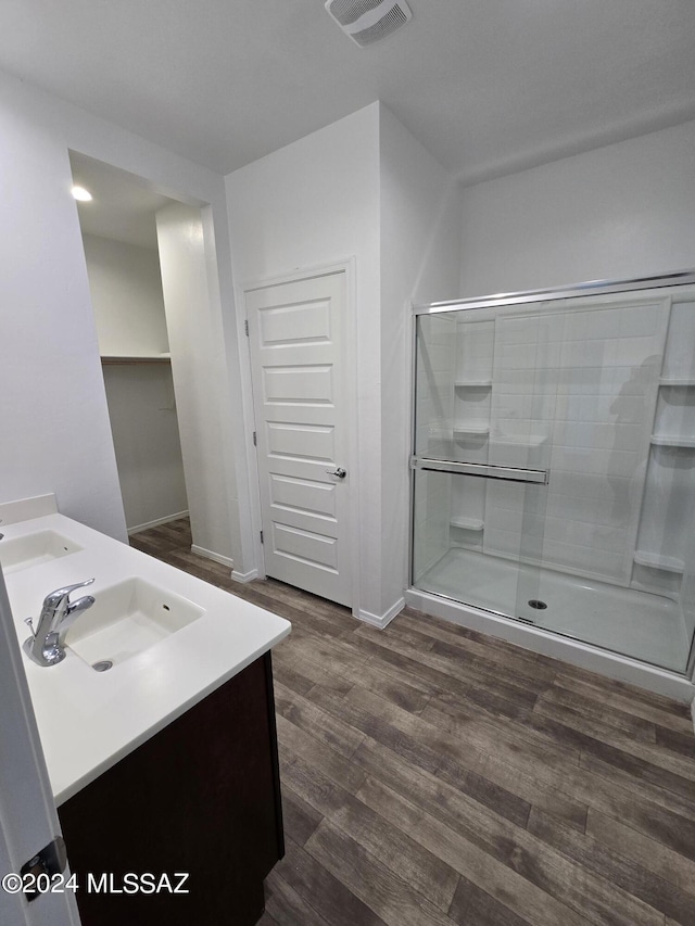 bathroom with a sink, double vanity, visible vents, a stall shower, and wood finished floors