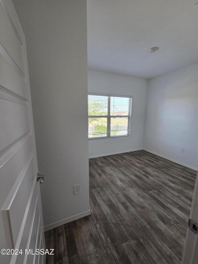 unfurnished room with dark wood finished floors and baseboards