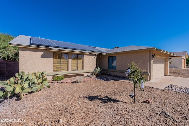 ranch-style house featuring a garage and solar panels