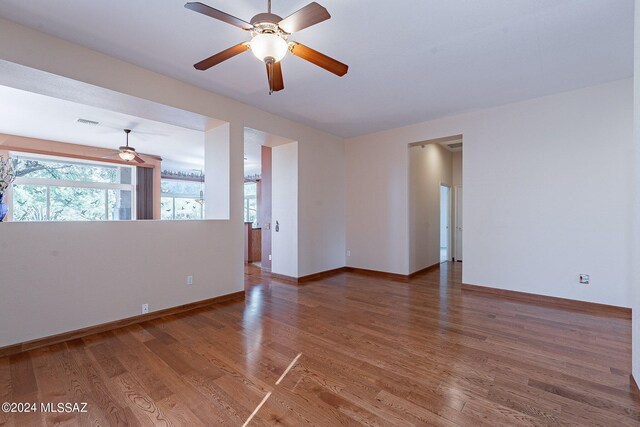 empty room featuring a wealth of natural light, hardwood / wood-style flooring, and ceiling fan