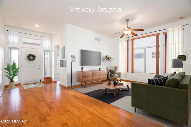 living room with a ceiling fan, visible vents, a wealth of natural light, and light wood-style floors