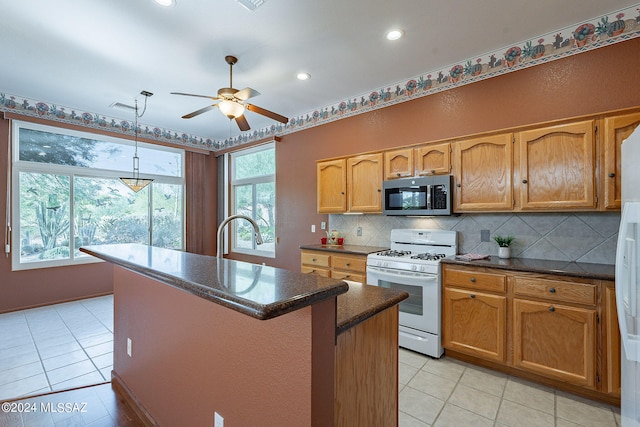 kitchen with a kitchen island, white gas range oven, sink, decorative light fixtures, and ceiling fan