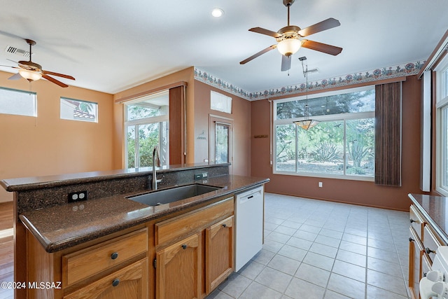 kitchen featuring dark stone countertops, white dishwasher, sink, and plenty of natural light