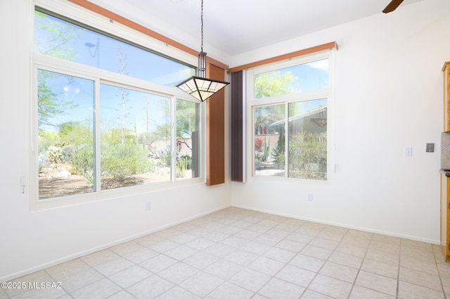 unfurnished dining area with baseboards, a ceiling fan, and light tile patterned floors