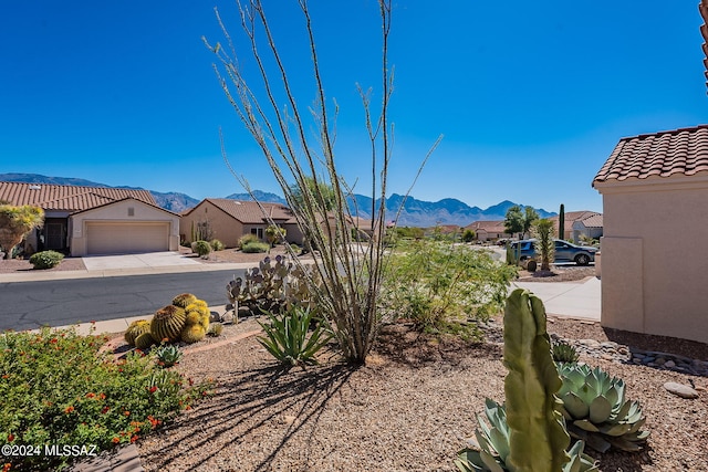 view of yard featuring driveway, an attached garage, a residential view, and a mountain view