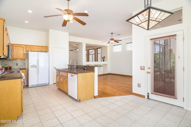 kitchen featuring a ceiling fan, a sink, dark countertops, and white appliances