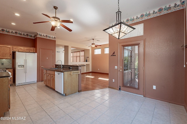 kitchen with dark countertops, white appliances, backsplash, and a sink