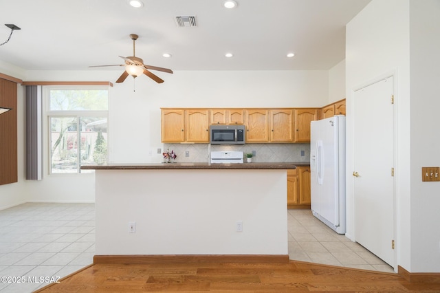 kitchen with white refrigerator with ice dispenser, stove, a ceiling fan, stainless steel microwave, and visible vents