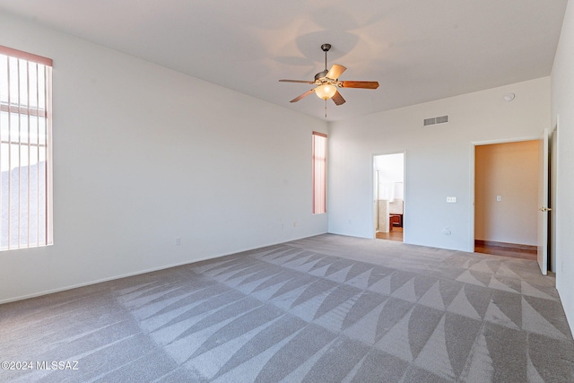 unfurnished bedroom with light carpet, connected bathroom, visible vents, and a ceiling fan