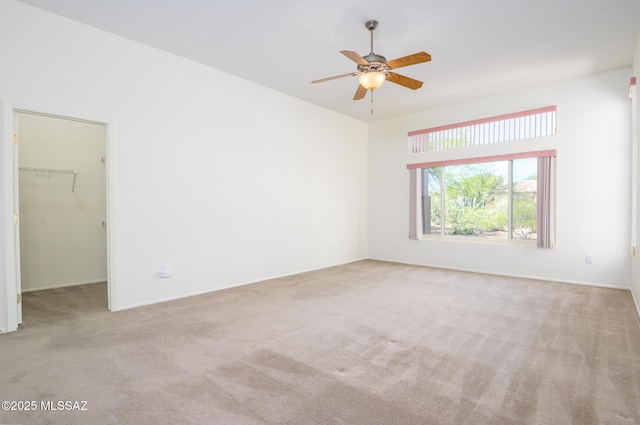 carpeted spare room with a ceiling fan and baseboards