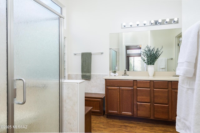 full bathroom with double vanity, a sink, a shower stall, and wood finished floors