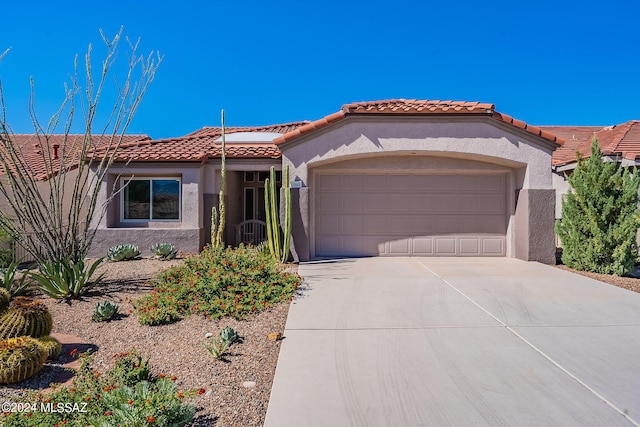 mediterranean / spanish-style house featuring a garage, a tile roof, concrete driveway, and stucco siding