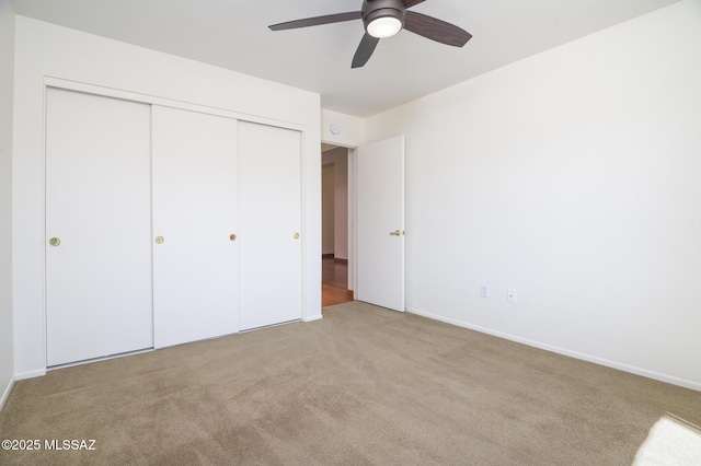 unfurnished bedroom featuring carpet floors, baseboards, ceiling fan, and a closet