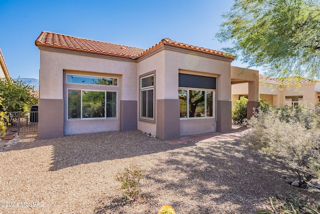 back of property with fence, a tile roof, and stucco siding