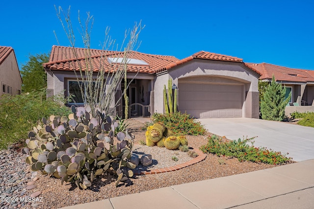 mediterranean / spanish house featuring a garage, concrete driveway, a tile roof, and stucco siding