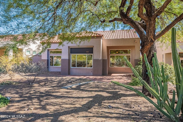 exterior space with a tile roof and stucco siding