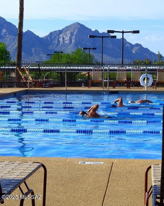 pool featuring a water slide, fence, and a mountain view
