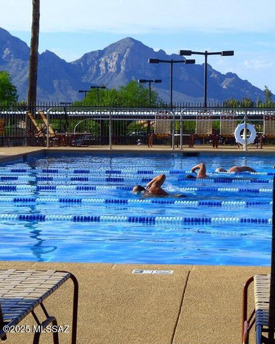 pool with a water slide, a mountain view, and fence