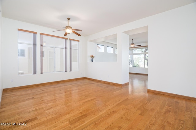 spare room featuring baseboards, a ceiling fan, and light wood finished floors