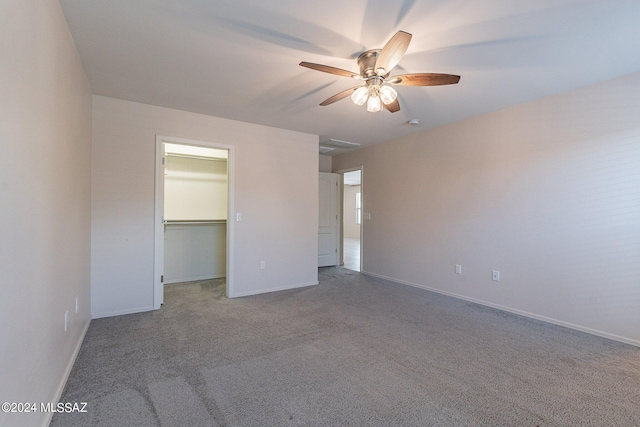 unfurnished bedroom with a spacious closet, carpet floors, a closet, and ceiling fan