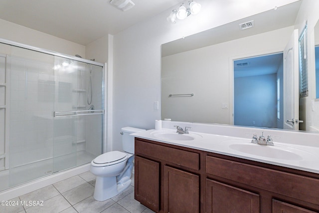 bathroom featuring toilet, a shower with shower door, vanity, and tile patterned floors