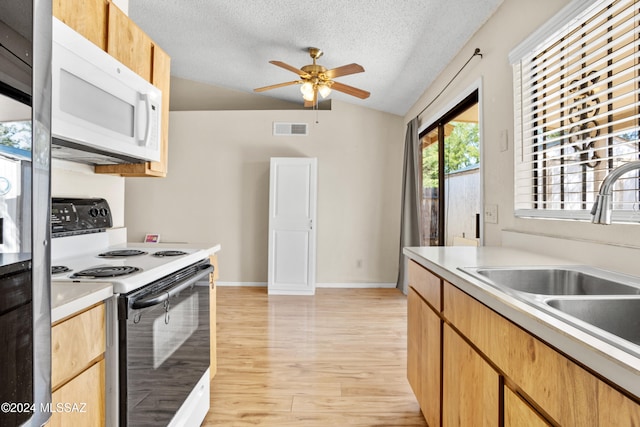 kitchen with white appliances, sink, a textured ceiling, light hardwood / wood-style floors, and vaulted ceiling