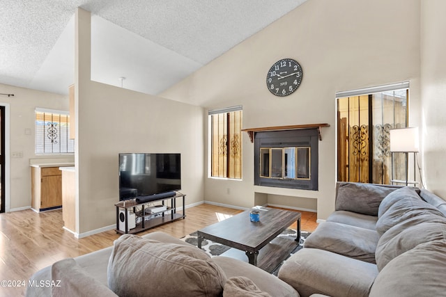 living room featuring light hardwood / wood-style floors, a textured ceiling, and high vaulted ceiling