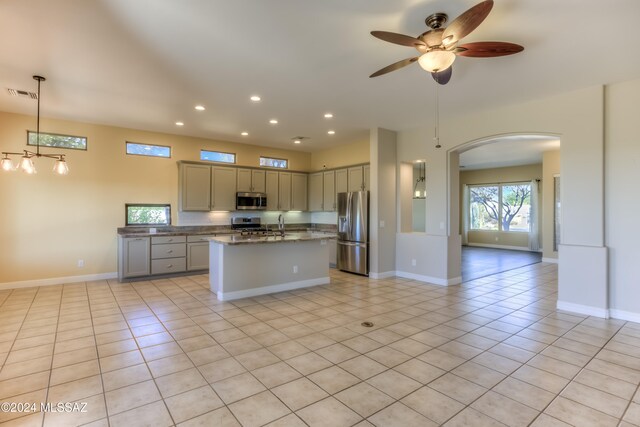 kitchen with appliances with stainless steel finishes, a kitchen island, dark stone counters, pendant lighting, and gray cabinets