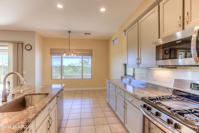 kitchen with sink, appliances with stainless steel finishes, light stone counters, and a healthy amount of sunlight