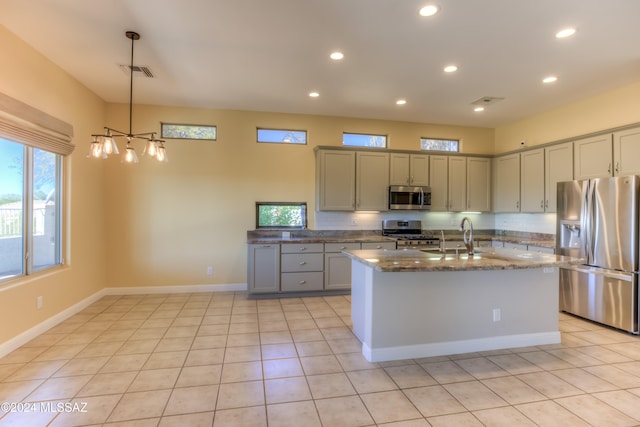 kitchen featuring light tile patterned floors, dark stone counters, sink, pendant lighting, and stainless steel appliances