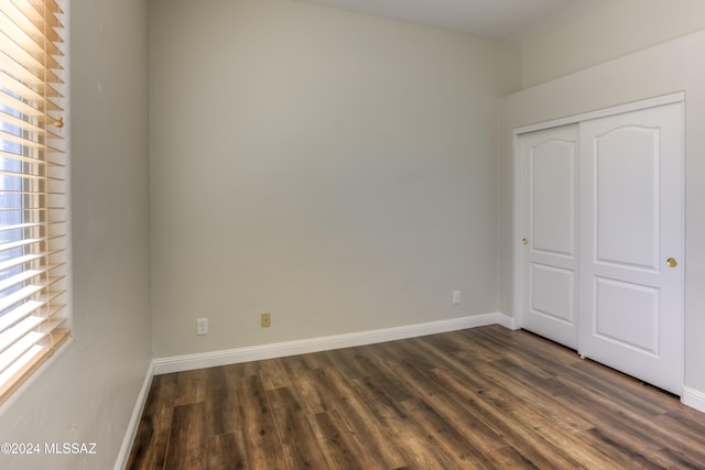 unfurnished bedroom with dark wood-type flooring and a closet