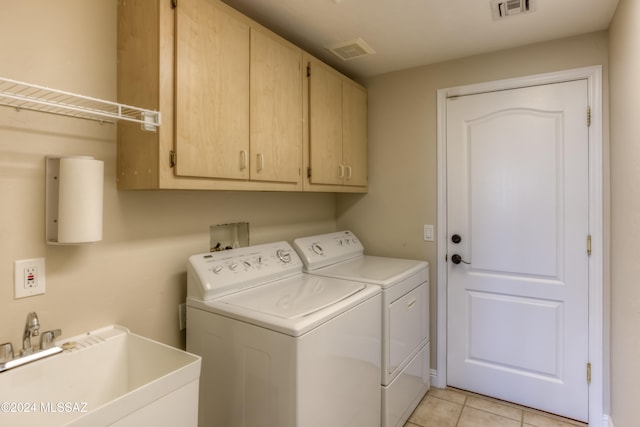 laundry area featuring light tile patterned flooring, cabinets, sink, and separate washer and dryer