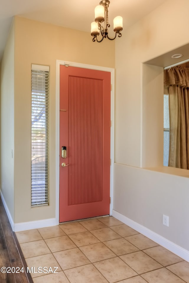 tiled entryway with a chandelier